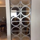 A decorative partition with circular patterns separates two rooms, revealing furniture in the background.