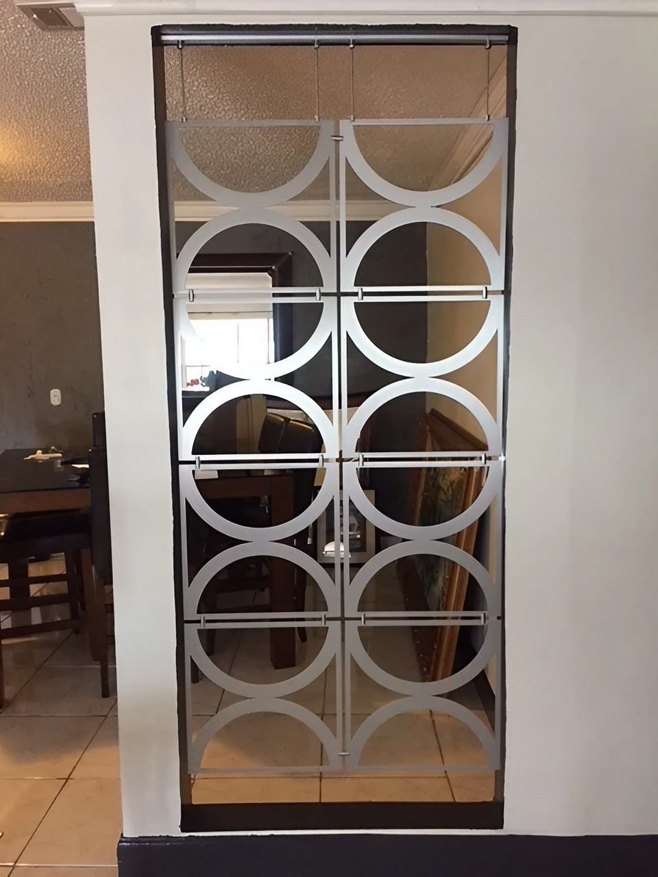 A decorative partition with circular patterns separates two rooms, revealing furniture in the background.