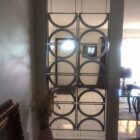 A decorative screen with circular patterns separates two rooms, showcasing a doorway and furniture beyond.