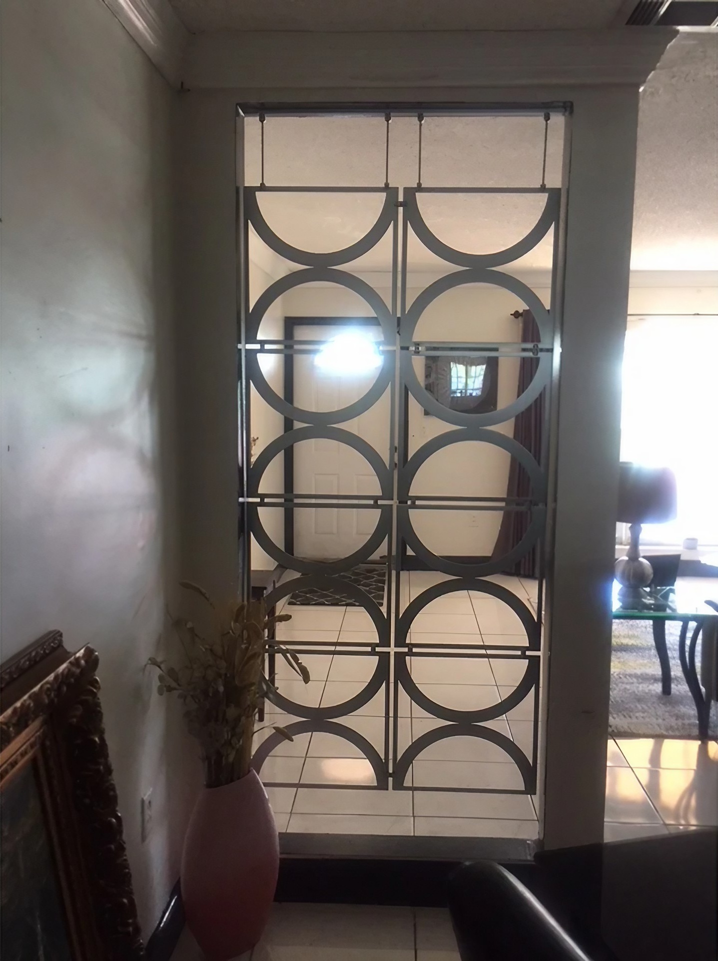 A decorative screen with circular patterns separates two rooms, showcasing a doorway and furniture beyond.