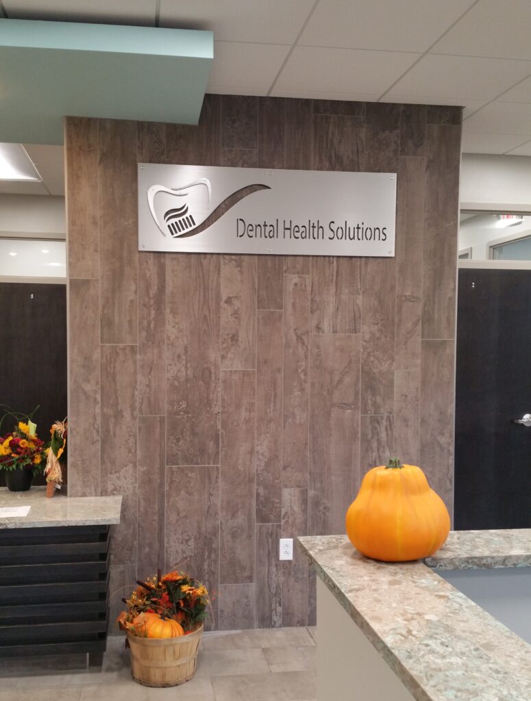 custom-sign-for-dentists-office-3 Dental office reception area with a sign, decorative pumpkin, and flowers in a basket.