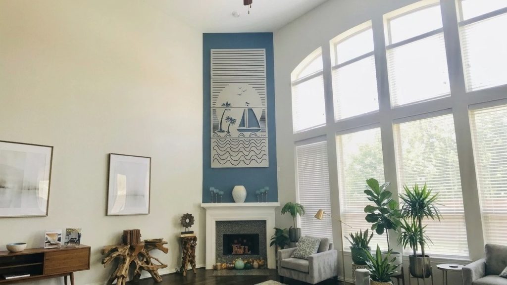 Bright living room with large windows, decorative wall art, plants, and cozy seating.