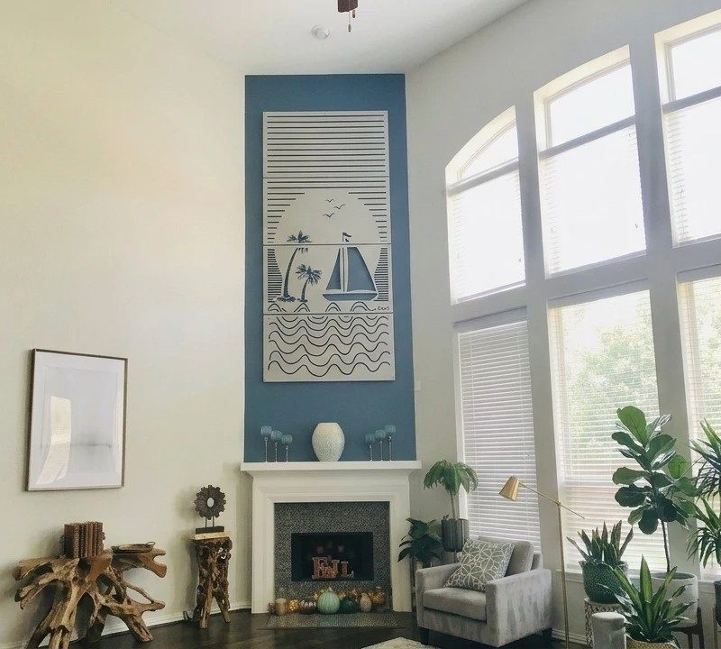 Bright living room with large windows, decorative wall art, plants, and cozy seating.