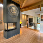 Medusa metal wall art above a modern fireplace in a spacious, wooden-floored living area.