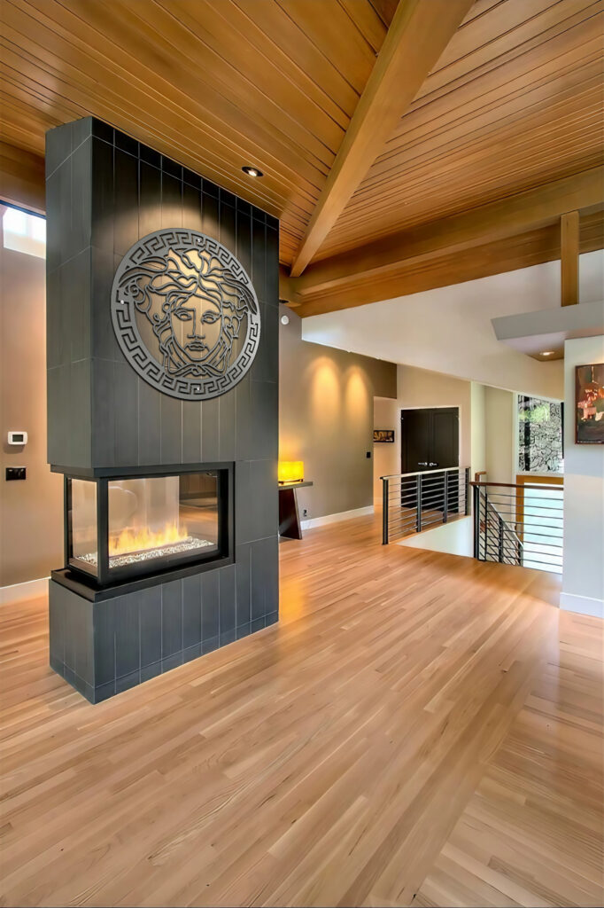 Medusa metal wall art above a modern fireplace in a spacious, wooden-floored living area.