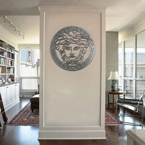 Medusa wall art displayed on a white wall in a modern living room. Bookshelves and furniture visible.