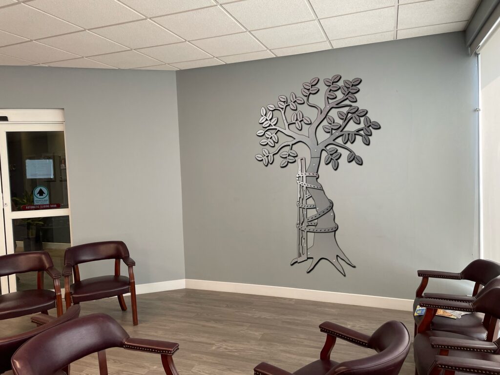A waiting area with brown chairs and a decorative tree mural on the wall.