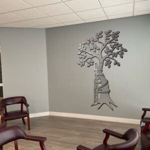 A waiting area with brown chairs and a decorative tree mural on the wall.