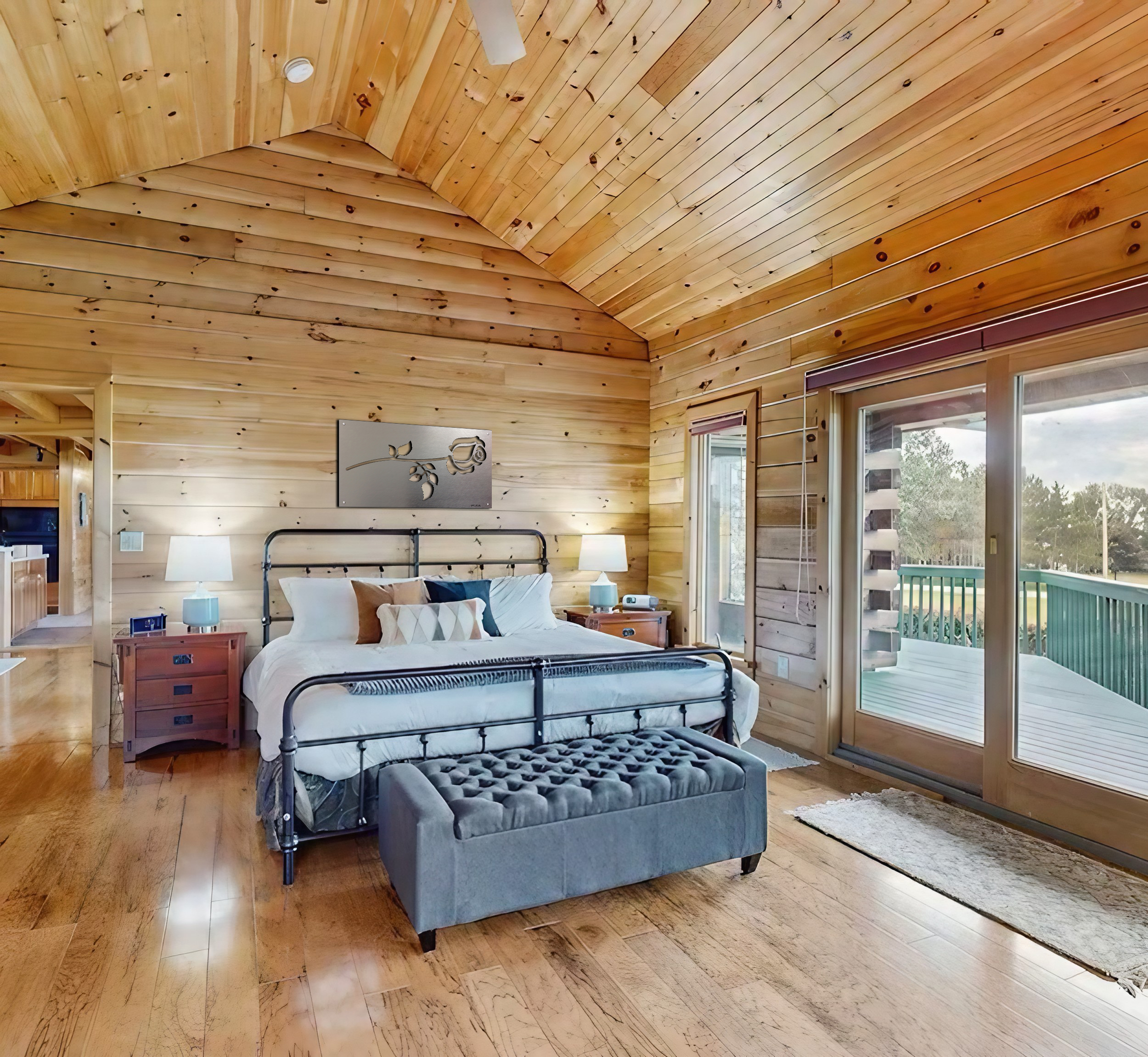Cozy bedroom with wooden walls, a bed, nightstands, and sliding doors to a deck.
