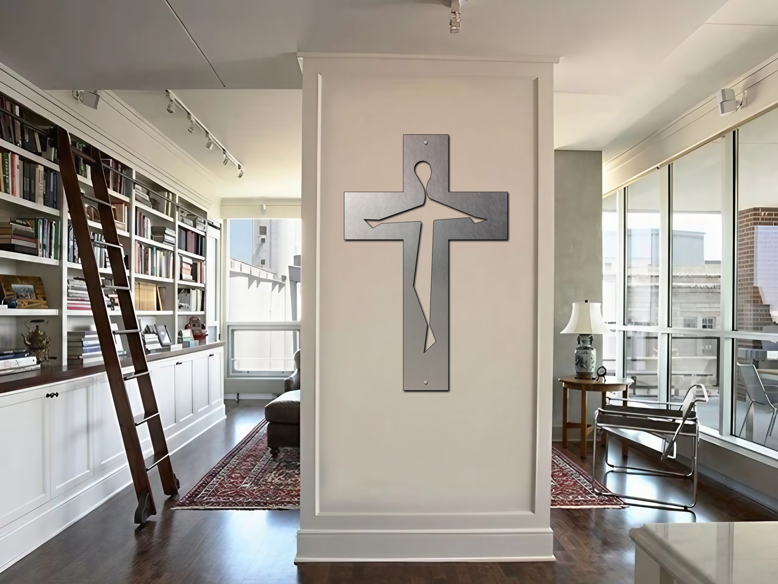 A modern crucifix hangs on a wall in a stylish living room with bookshelves and a ladder.