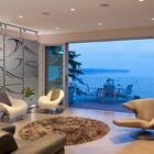 Modern living room with a wave-patterned room divider, stylish chairs, and a view of the ocean.