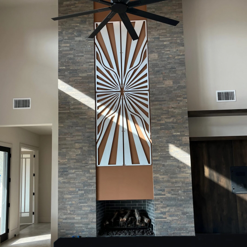 Modern living space featuring a large ceiling fan, stone wall, and decorative fireplace with geometric art.