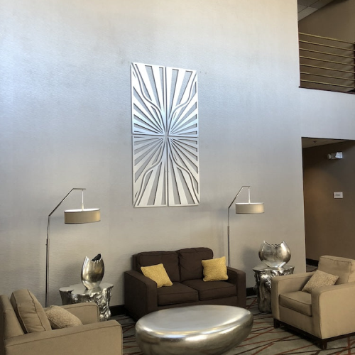 Modern lounge area with brown sofas, silver coffee table, and decorative wall art.
