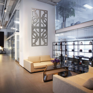 Modern lounge area with beige sofas, a glass table, and decorative wall art. A plant is visible through glass partitions.