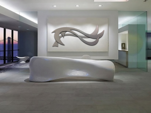 Modern interior features a sleek white bench and abstract wall art, with large windows showing a sunset view.